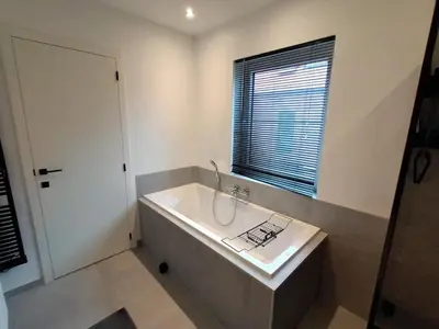 a white bathroom with a tub and a window at TML House in Boom