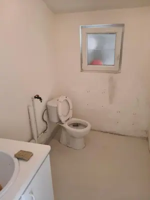 a bathroom with a toilet and a window at De roze kamer in Mol