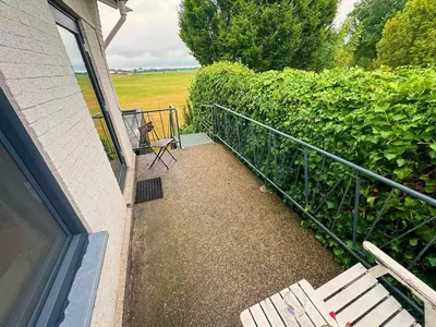 a balcony with two white chairs and a fence at Villa Grenszicht in Nispen