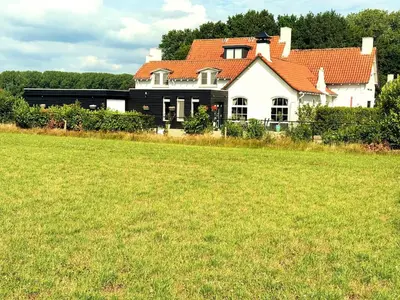a large house with a grass field in front of it at Villa Grenszicht in Nispen