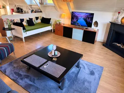 a living room with a couch and a table and a tv at Villa Grenszicht in Nispen
