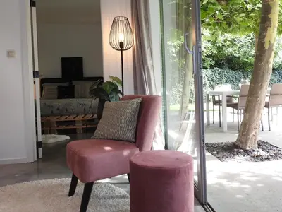 a pink chair and a stool in a living room at Casa Milo in Lokeren