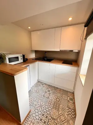 a kitchen with white cabinets and a microwave at Studio with sauna in Meise