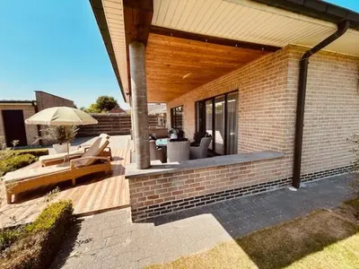 a patio with chairs and an umbrella on a house at Charmante woning in de Vlaamse Ardennen in Sint-Lievens-Houtem