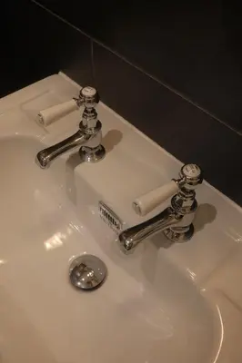 a bathroom sink with two faucets and a drain at Studio Nolo by Simone Antwerp in Antwerp
