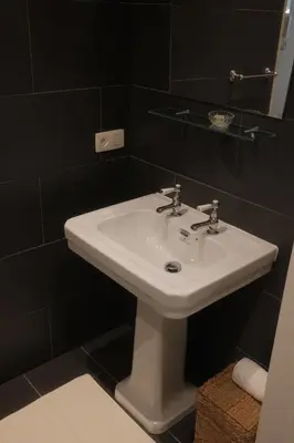 a white sink in a bathroom with black tiles at Studio Nolo by Simone Antwerp in Antwerp