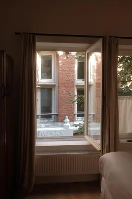 a bedroom window with a view of a brick building at Studio Nolo by Simone Antwerp in Antwerp