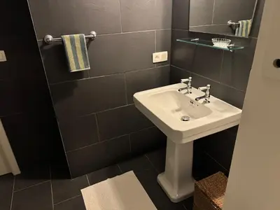 a bathroom with a white sink and black tiles at Studio Nolo by Simone Antwerp in Antwerp
