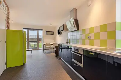 a kitchen with green and yellow tiles on the wall at Klavertje Lier Schapenstal in Lier