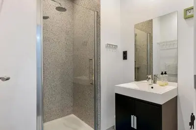 a bathroom with a shower with a sink and a mirror at Klavertje Lier Schapenstal in Lier