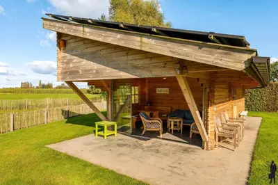 a wooden pavilion with a table and chairs in a yard at Klavertje Lier Schapenstal in Lier