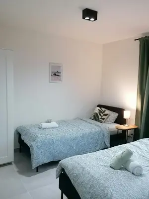 a bedroom with two beds and a table with a lamp at Sandrise in Balen