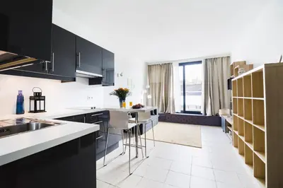 a kitchen with black cabinets and a white tile floor at Brussels St Gilles Elegant residence in Brussels