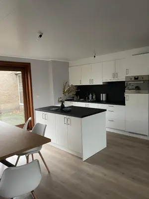 a kitchen with white cabinets and a table and chairs at Rent and Relax Geel in Geel