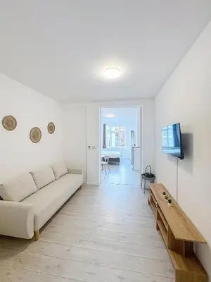a white living room with a couch and a table at Spacieux appartement une chambre in Brussels