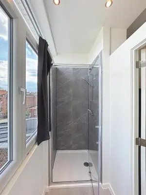 a glass shower in a bathroom with a window at Spacieux appartement une chambre in Brussels