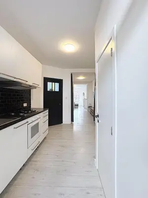 an empty kitchen with white cabinets and a hallway at Spacieux appartement une chambre in Brussels
