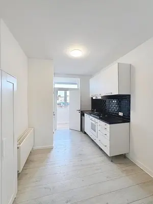 a kitchen with white cabinets and a black counter top at Spacieux appartement une chambre in Brussels