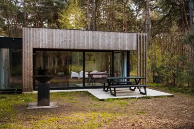 a house in the woods with a bench and a table at Knuscabin in Lille