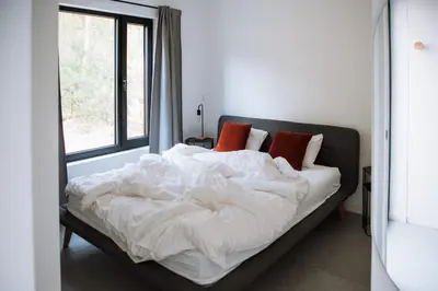 a bedroom with a bed with white sheets and a window at Knuscabin in Lille