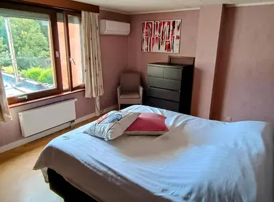 a bedroom with a bed and a chair and a window at Rustig gelegen woning in Tielrode in Temse