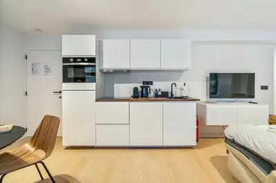 a white kitchen with white cabinets and a table at Gezellig & Centraal - 4 Persoons Gentse Studio in Ghent