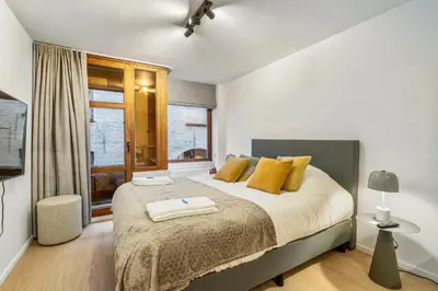 a bedroom with a large bed with yellow pillows at Charmante Studio op Toplocatie - Hartje Gent in Ghent