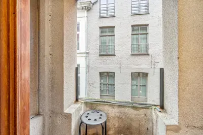 a chair sitting in front of a window with a building at Charmante Studio op Toplocatie - Hartje Gent in Ghent