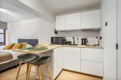 a white kitchen with a bed and a table and chairs at Charmante Studio op Toplocatie - Hartje Gent in Ghent