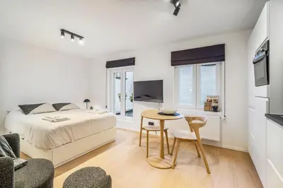 a white bedroom with a bed and a table at Gezellige Gentse Studio - Perfect Voor Koppels in Ghent