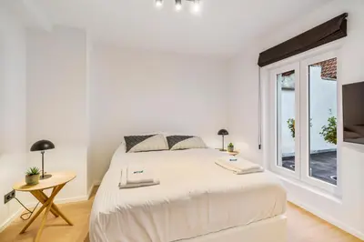 a white bedroom with a large bed and a window at Gezellige Gentse Studio - Perfect Voor Koppels in Ghent