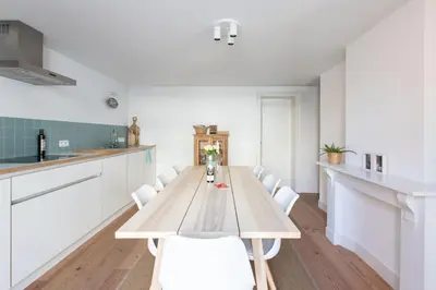 a kitchen with a wooden table and white chairs at Charming duplex apartment with spectacular views in Antwerp