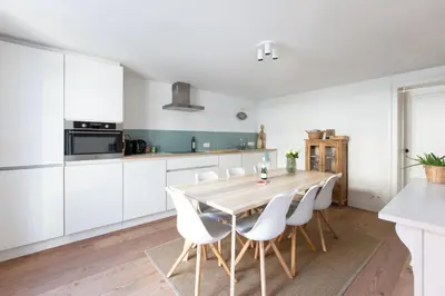 a kitchen with white cabinets and a wooden table and chairs at Charming duplex apartment with spectacular views in Antwerp