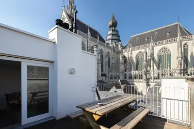 a wooden bench on a balcony in front of a cathedral at Charming duplex apartment with spectacular views in Antwerp