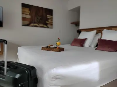 a bedroom with a large white bed with a suitcase at het Boekenhof in Niel