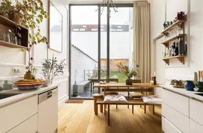 a kitchen with white cabinets and a table and a window at Cozy Room with Garden in Brussels