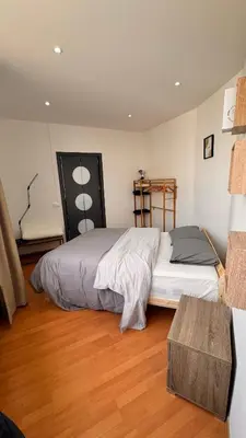 a bedroom with a large bed and a wooden floor at T2 Neuf Quartier Calme central et transport devant in Brussels