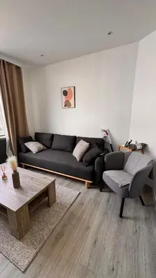 a living room with a black couch and a coffee table at T2 Neuf Quartier Calme central et transport devant in Brussels