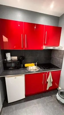 a kitchen with red cabinets and a sink at T2 Neuf Quartier Calme central et transport devant in Brussels