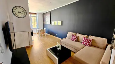 a living room with a couch and a clock on the wall at Suite Diamant - Chic & Lumineux in Brussels