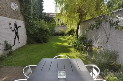 a table in a garden with a painting of a man holding a ball at Apartment Home Frit Home in Brussels