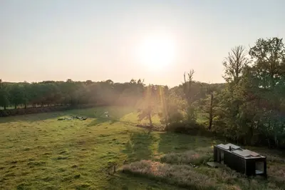 a field with a shed in the middle of a field at Gorgeous Off-Grid Tiny House Near Antwerp, Belgium in Wuustwezel
