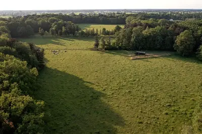 an aerial view of a field with a barn in the middle at Gorgeous Off-Grid Tiny House Near Antwerp, Belgium in Wuustwezel
