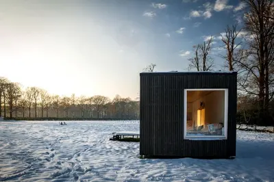 a small building in the snow in a field at Gorgeous Off-Grid Tiny House Near Antwerp, Belgium in Wuustwezel