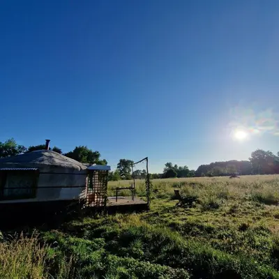 a house in a field with the sun in the sky at Strackxhoeve Yurt 'Haardpeer' in Laakdal