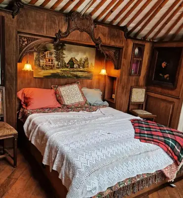 a bedroom with a large bed with wooden walls at Strackxhoeve Yurt 'Haardpeer' in Laakdal