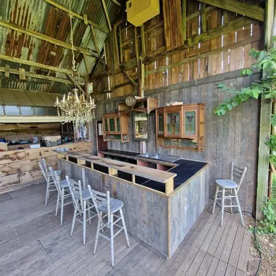 an outdoor kitchen with chairs and a bar in a barn at Strackxhoeve Yurt 'Haardpeer' in Laakdal