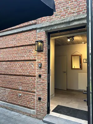 an open garage door with a brick wall at Comfortabele groepswoning voor 8 met ruimte tuin in Turnhout