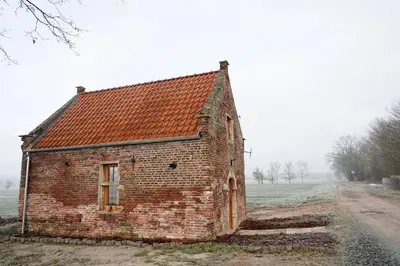 an old brick building sitting in a field at Bakkershuisje Kraneveldhoeve in Haacht