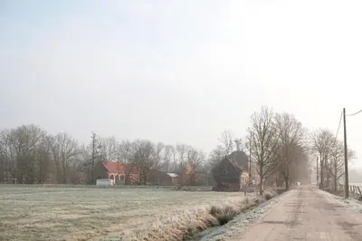 a field with a house and a dirt road at Bakkershuisje Kraneveldhoeve in Haacht